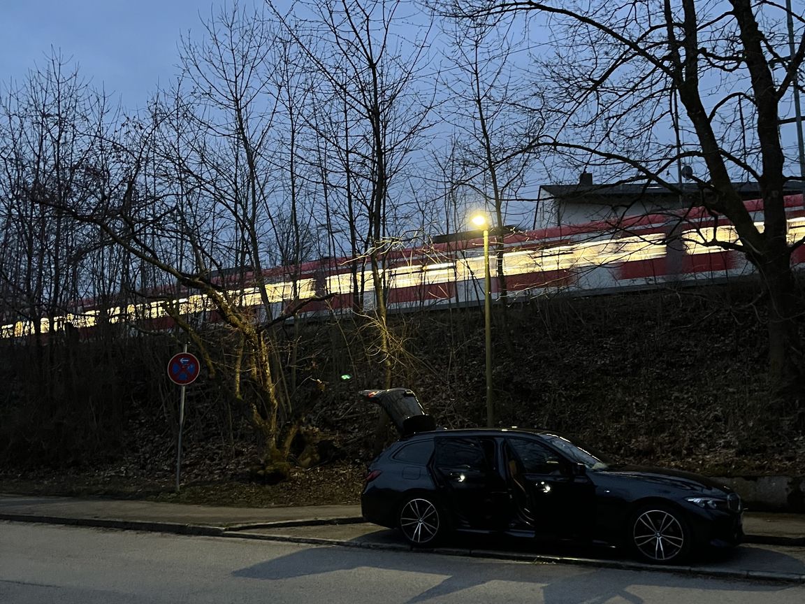 Our rental car in the dusk, unpacked, with a train running behind it